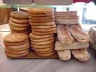 Pile di pagnottelle bianche su un banco di forno — il pane base del «cinque e cinque», il panino della cucina ebraica livornese.
